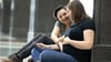 Lesbian couple sitting looking at sonogram with hands on pregnant belly